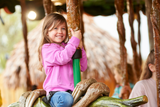 Young girl rides on the carousel at Drusillas near Brighton.